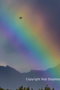 Arc of a rainbow with an aircraft flying through it